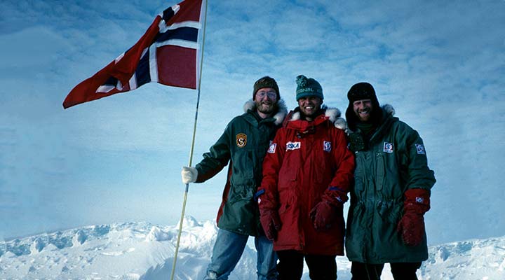 three mountaineers on summit with norweigian flag